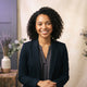 A diverse woman with a friendly expression posing for a professional headshot against a neutral studio background.